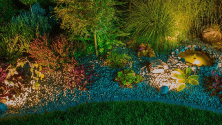 A vibrant nighttime shot of a rock garden and landscaping illuminated by colorful LED lights, showcasing a professional lighting design.
